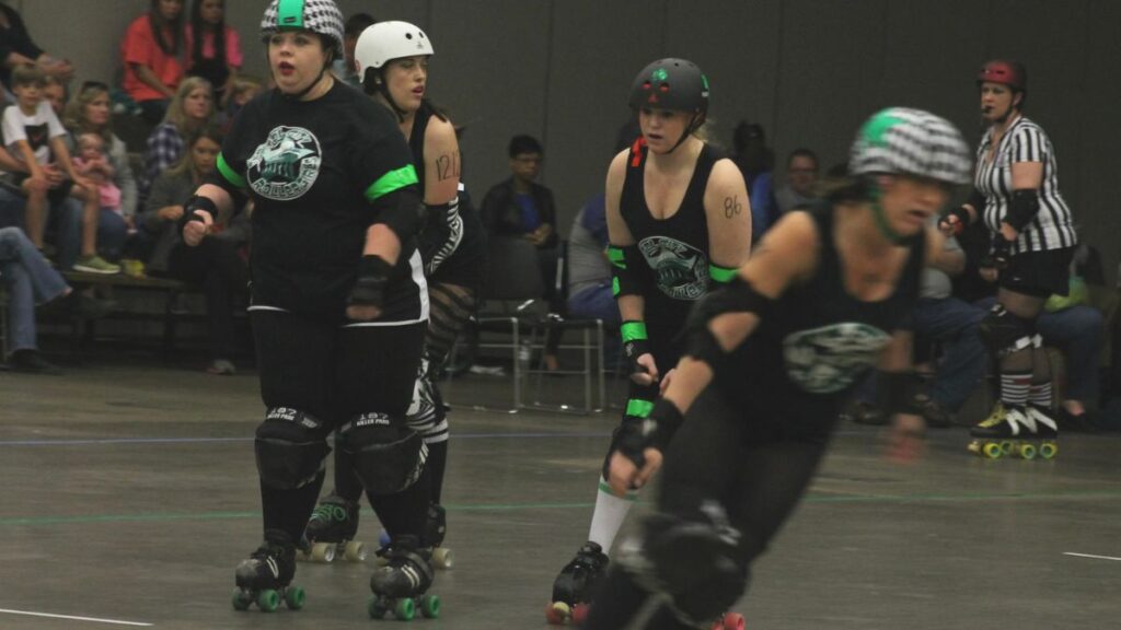Roller derby jammer pushing through blockers during a jam on a flat track